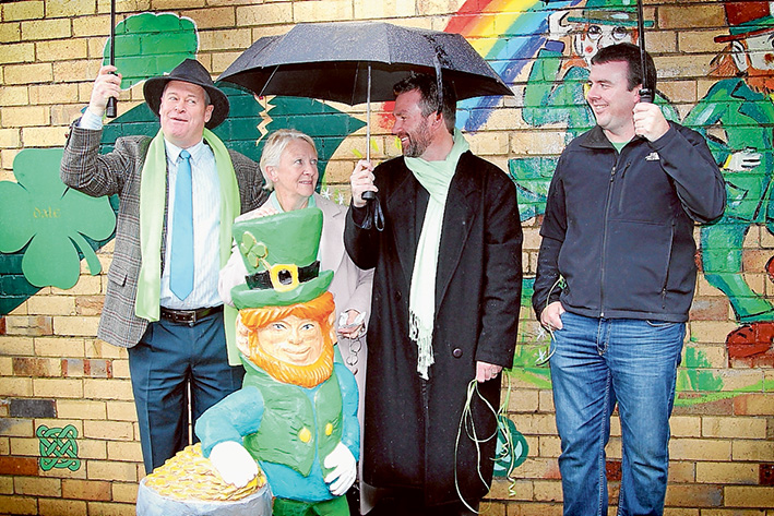 Lots of rain, but memories shine: Councillor David Garnock (left), Bridget O’Toole with two of her sons, Christian and Trent. They stand behind a leprechaun carving by Angie Polglaze. Picture: Cameron McCullough