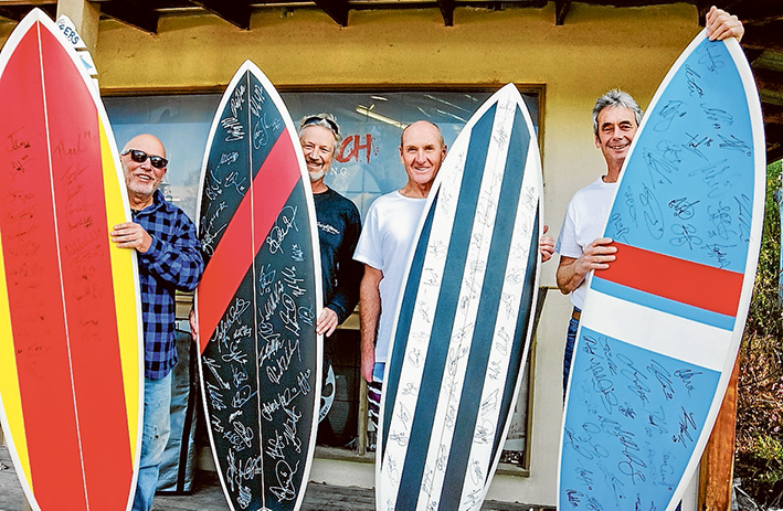 Signed up: Four of the “footy boards” to be auctioned to raise money for the Disabled Surfers Association Mornington Peninsula branch with, from left, branch president Joe Hart, Rod Jones (Triple R’s Dr Surf), boardmaker Phil Trigger and committee member John Bowers.