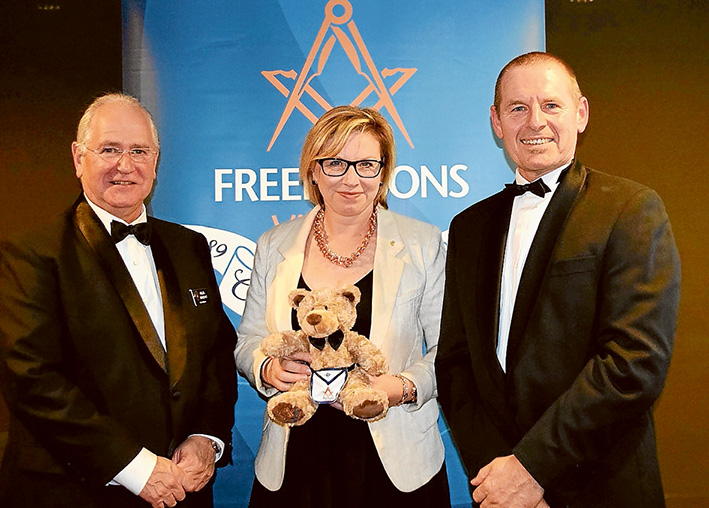 Like minds: Grand Master Freemasons Victoria Hellel Benedykt, Australian of the Year Rosie Batty, and Master of Mornington Lodge Edy Wilfling with Lewis the Bear. He has been sold to raise money for the “Never Alone” Luke Batty Foundation. Picture: Marg Harrison