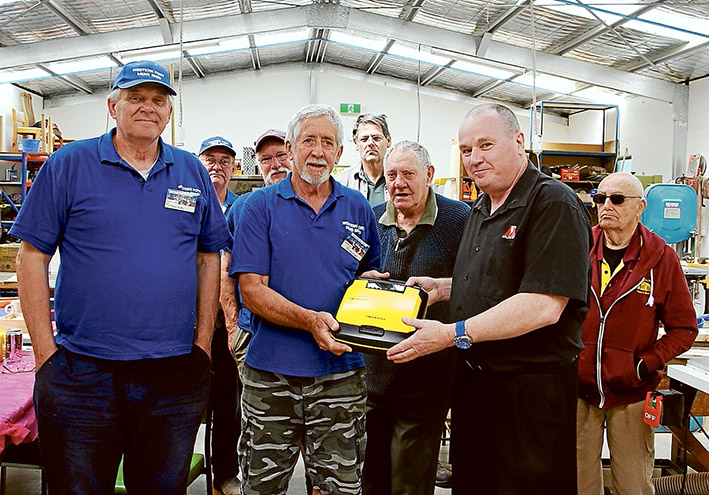 Life saver: Western Port (Hastings) Men’s Shed secretary Colin Proud (centre, in blue) and training officer Andrew Clinkaberry show off the new defibrillator. 