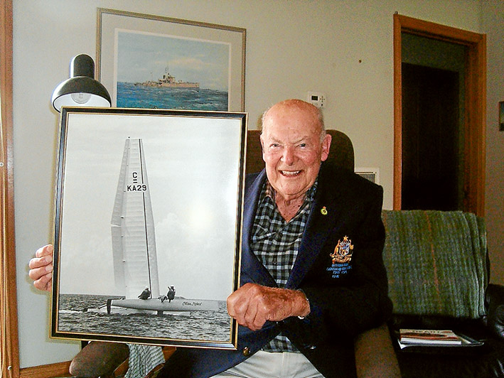 All abuzz: John Buzaglo of Mornington was awarded the Medal of the Order of Australia on 26 January for services to yachting. He is holding a photo of Miss Nylex, the “wingsail” catamaran that revolutionised international yacht racing including the modern America’s Cup. Picture supplied