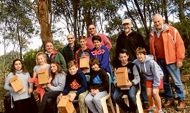 Home sweet home: Microbat home makers Trinity, Ollie, Floyd, Tarek, Seb, Flynn, Kira, Emily and Charlie with Mornington Men’s Shed members Bertil, Gary, Tony, Phil and Sean.