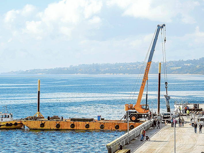 A crane aboard a barge is used to lift 15 tonne concrete panels which broke off Mornington pier during a stome two weeks ago. Picture: Yanni