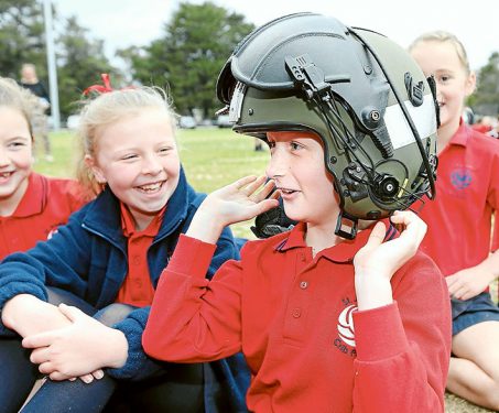 Madison Cruickshank of St Josephs Primary Schools tries on a pilots helmet during 723 Squadron visit to Cyril Fox Reserve, Crib Point, Victoria.