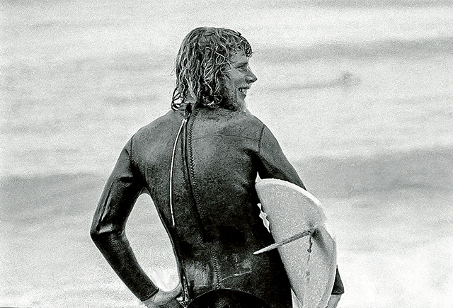 Top rider: Bernard “Midget” Farrelly, above, at Bells Beach in the mid-1970s and, below, with Doug “Claw” Warbrick one of the founders of Rip Curl and, bottom, cutting an occy strap to open the 1975 Surfworld exhibition with the Skyhooks frontman, the late Graeme “Shirley” Strachan. Pictures: Keith Platt