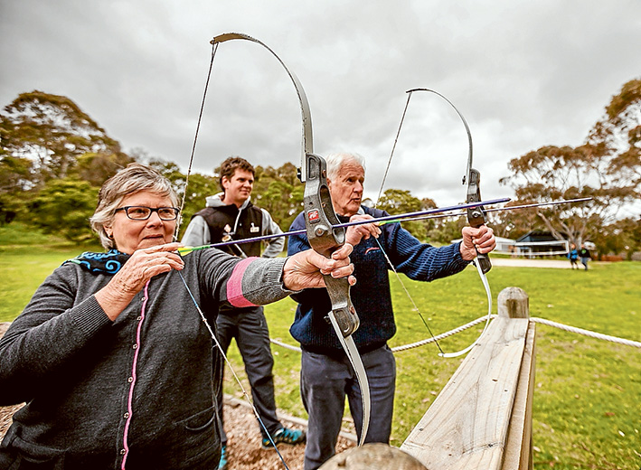 Taking aim: Camp Manyung’s Jim Boyle watches as Margaret and Kevin Begley experience try their hands at archery in the YMCA’s new seniors program. Picture: Yanni
