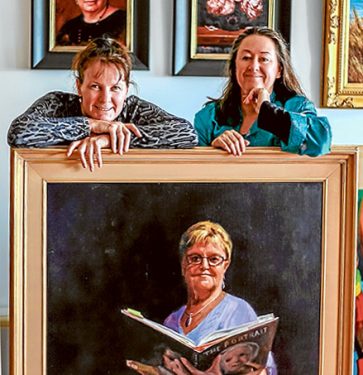 Doubling up: Fiona Bilbrough and Vicki Sullivan have combined their works for a portraits exhibition at Mornington Peninsula Regional Gallery. Theyt are pictured with Bilbrough’s “Attention Please” portrait of  former primary school principal, Carol Norman. Picture: Supplied