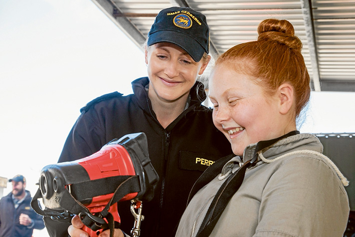Here’s how it’s done: Able Seaman Sarah Perry, of HMAS Cerberus, shows a heat detecting device in the firefighting area to Amber Haslem, of Balnarring, at the open day. Picture: Gary Sissons