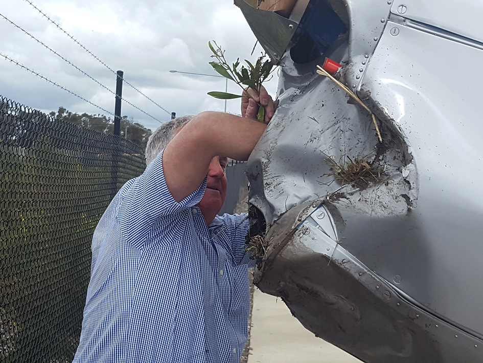 Graham Hosking removes debris from the intake at the front of his crashed plane. Picture: Cameron McCullough