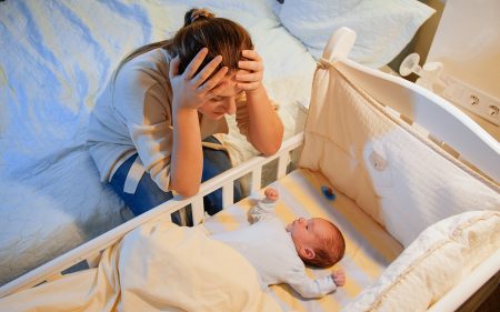 Stressed and tired mother looking at her baby