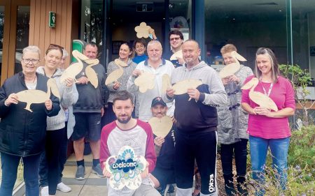 THE community is invited to select a sign to decorate in their individual style. Pictured are the team and volunteers at Kindred Clubhouse. Picture: Supplied